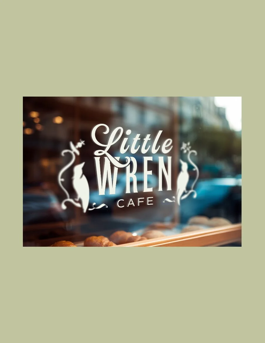 The Little Wren Cafe logo, a script-and-serif wordmark flanked by two perched birds, applied in white vinyl on a sunny café storefront window with pastries on the sill.