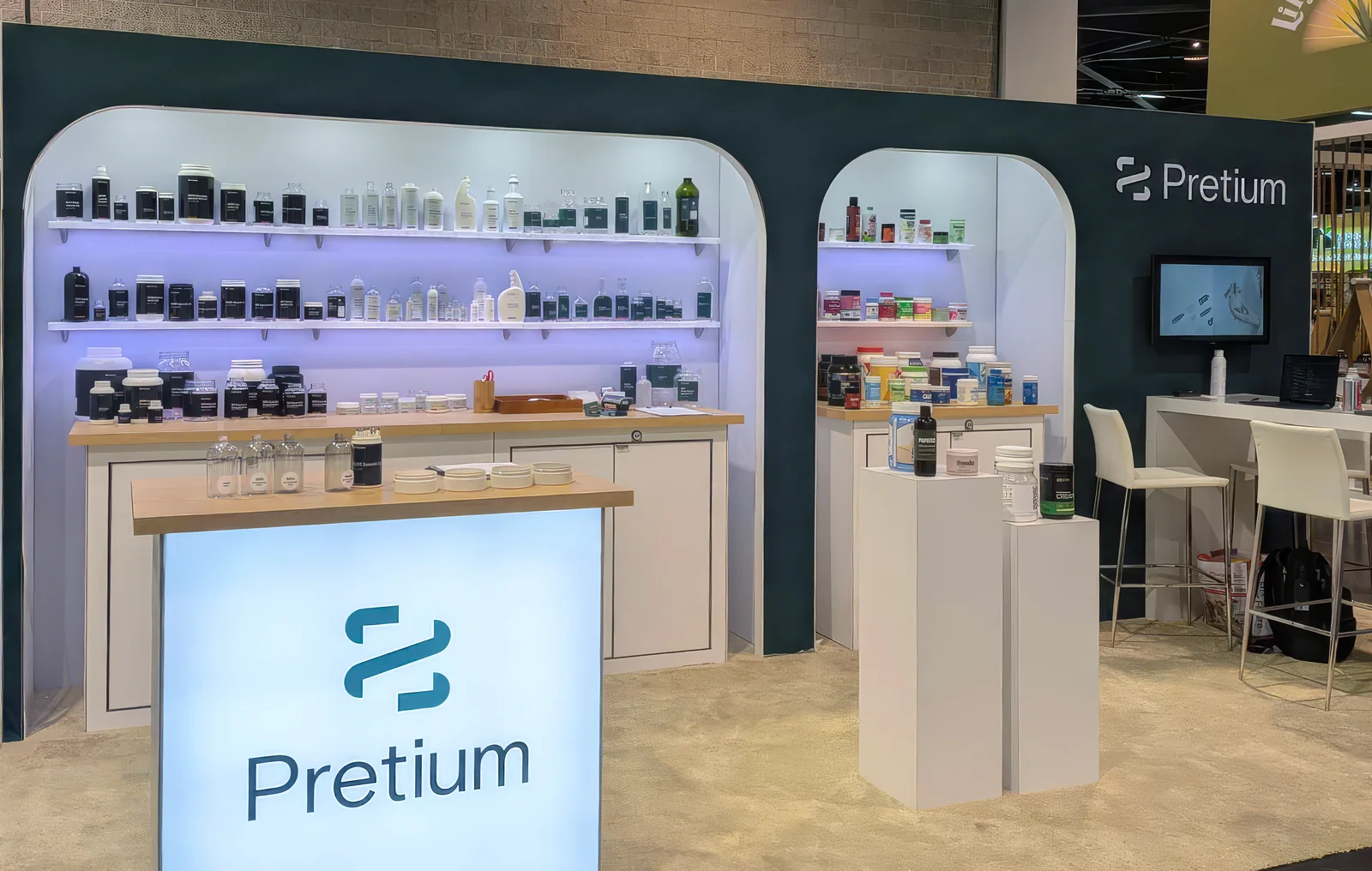 The Pretium trade-show booth at Natural Products Expo West, with sample bottles and jars and a looping brand video.